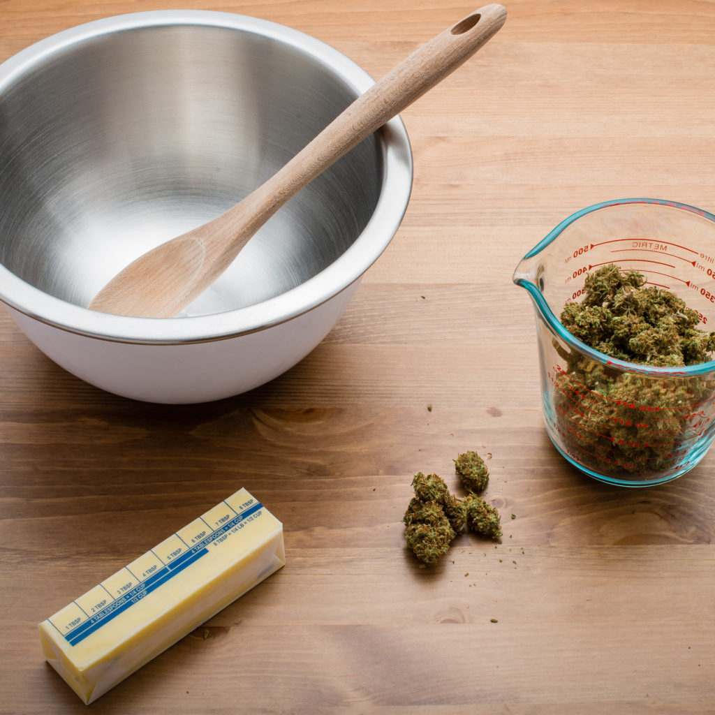 Cannabutter maken met een kom, houten lepel, boter en gedroogde cannabisbloemen