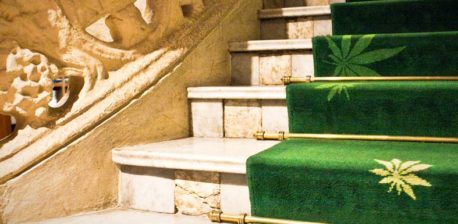 Stairs with green carpet that has cannabis leaf prints