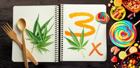 Un cuaderno con hojas de cannabis y número 3 y dulces al lado