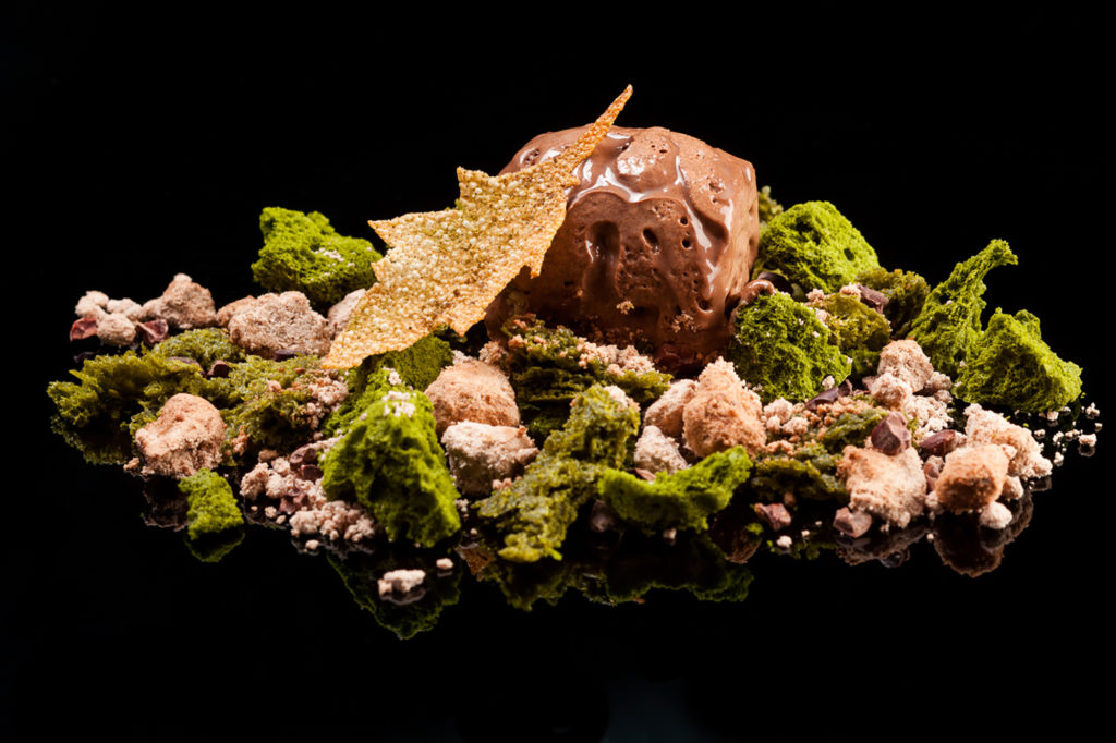 Een dessert van sponscake, bergled en een afbrokkelen van Carob Meel en gekarameliseerde hennepzaden