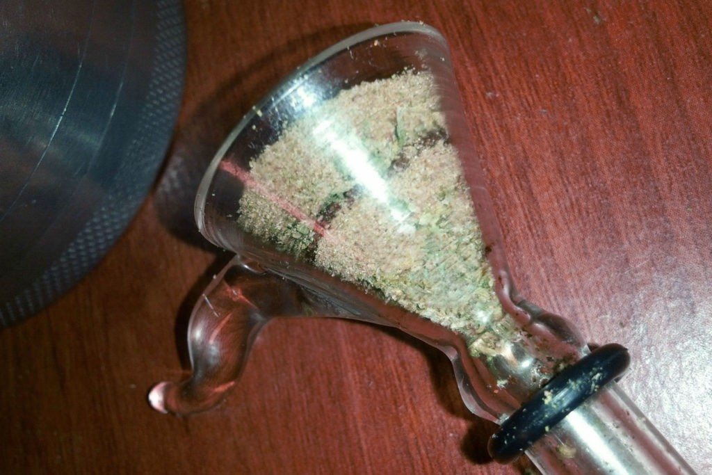 Kief en un tubo de cannabis en la superficie de madera