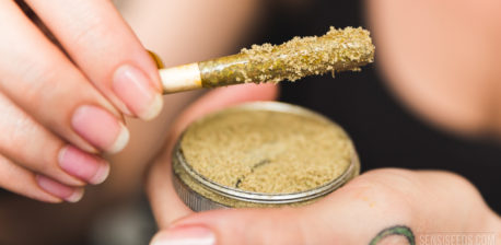 A woman holding a joint and an open tin of kief