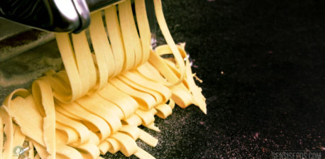 Een pasta-machine die gele hennep tagliatelle snijdt