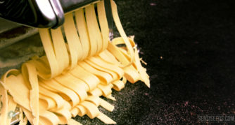 Eine Teigwarenmaschine, die gelbe Hanf-Tagliatelle schneidet