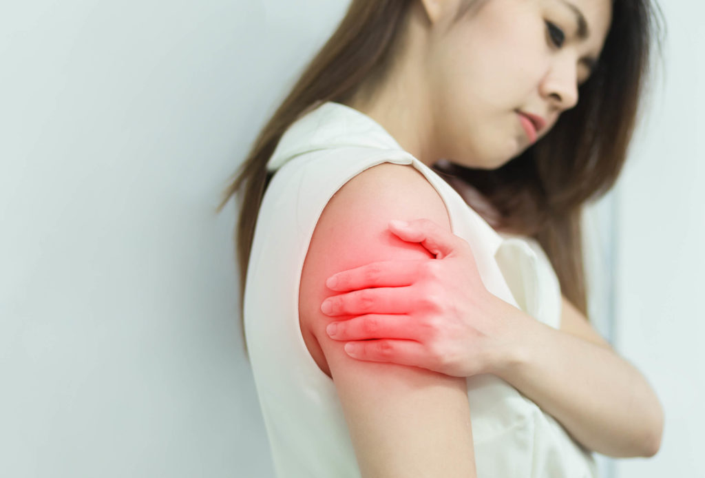 A brunet woman holding her aching arm 