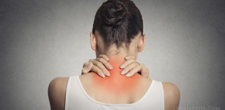 Una mujer sosteniendo su cuello, que es rojo e inflamado.