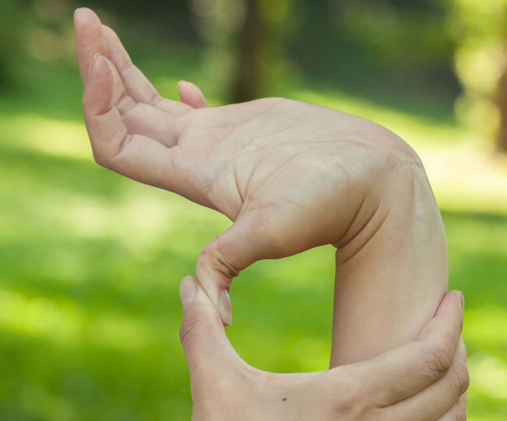 Someone using their hand to press their thumb backwards on the opposite hand