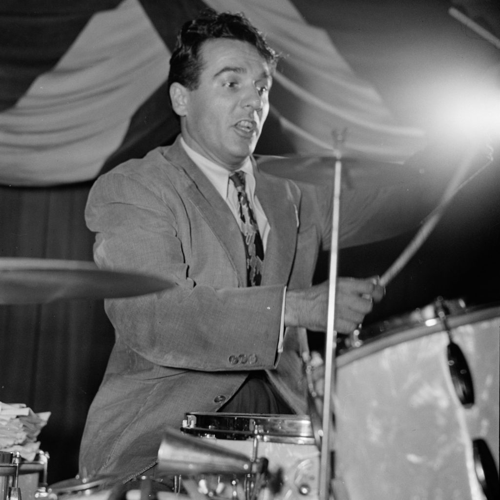 A man wearing a suit and playing the drums