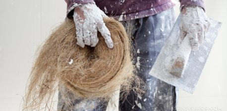 A person holding a hemp building material and trowel