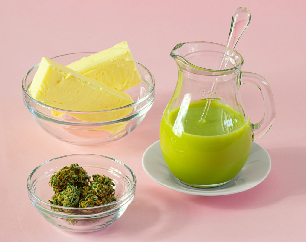 A cup with dried cannabis, a jug of cannabis topical and a cup of butter