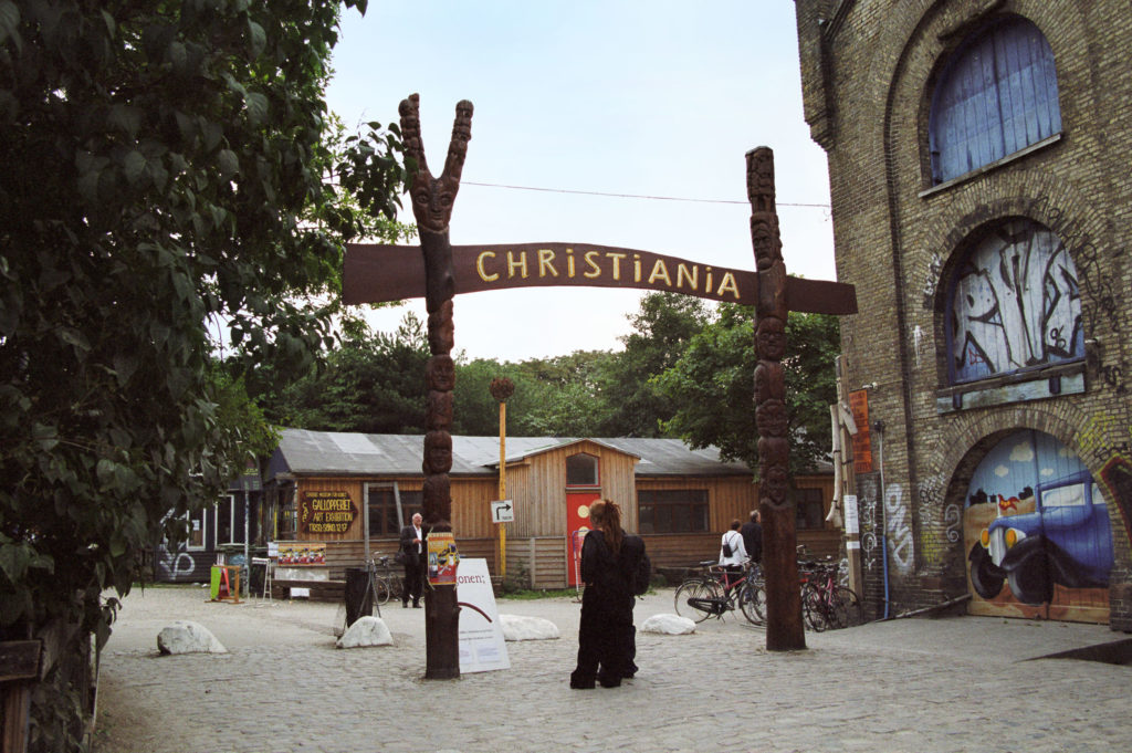 Totem Postes sosteniendo un signo 'Christiania' en la entrada a una ciudad