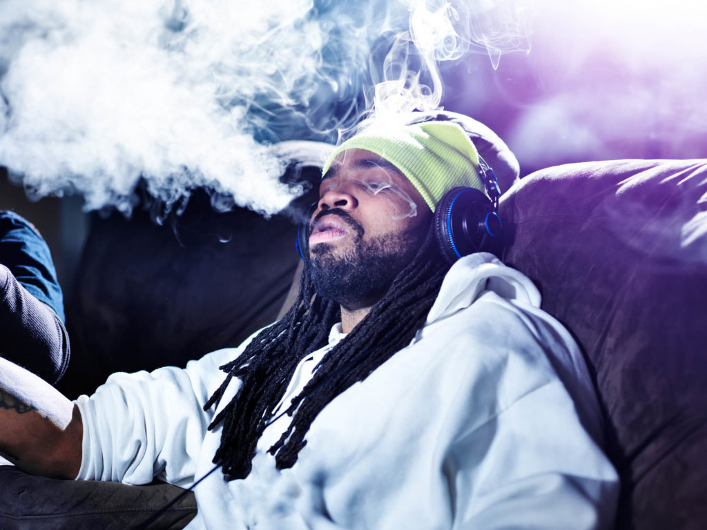 African-American man with dreadlocks smoking cannabis