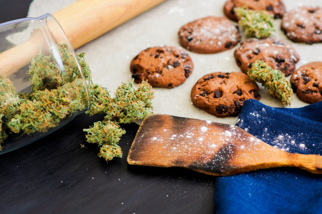 A rolling pin, wooden spoon, cookies and a jar of cannabis buds