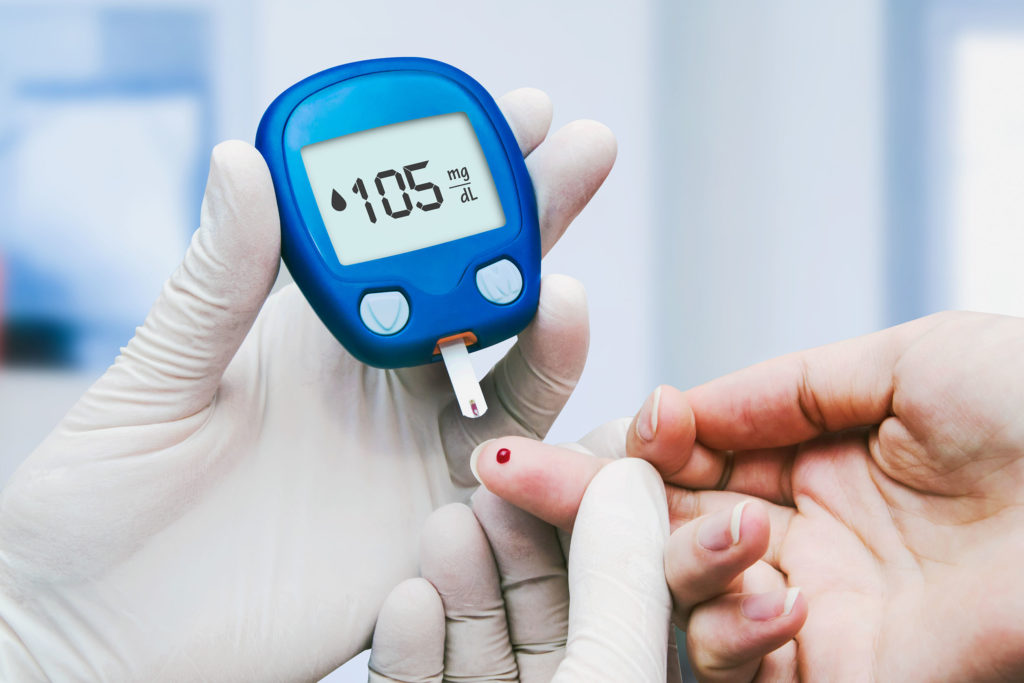 A doctor measuring blood sugar levels on a glucose meter on a patient