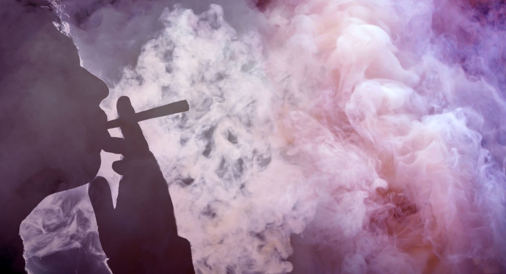 A silhouette of a person smoking a joint and lots of purple smoke