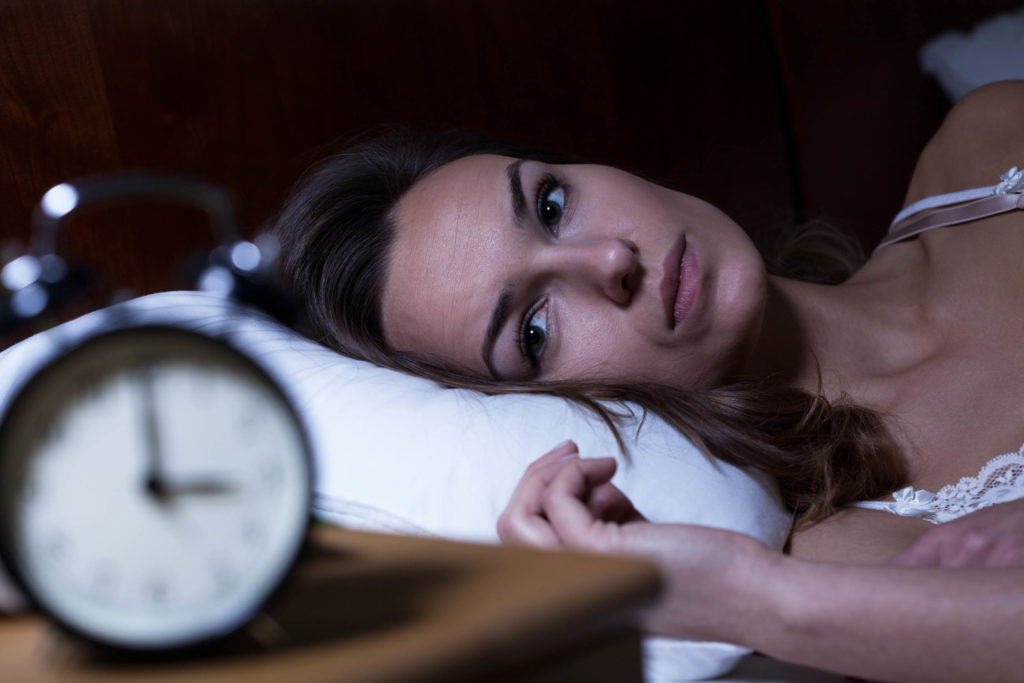 A woman lying in a bed looking at the clock