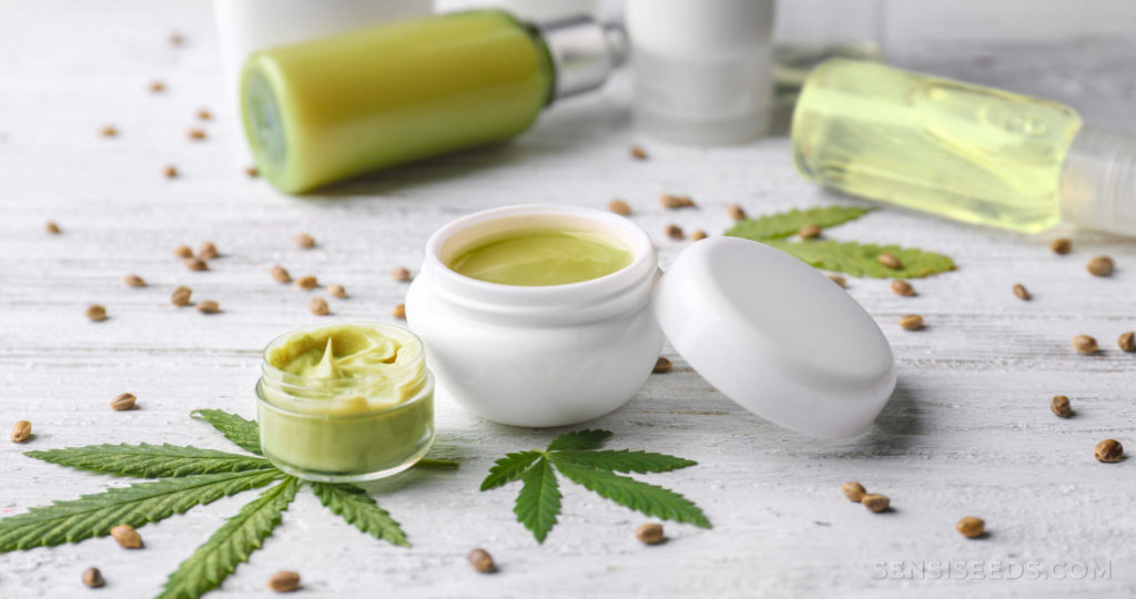 Various cannabis topicals on wooden surface with cannabis leaves and seeds