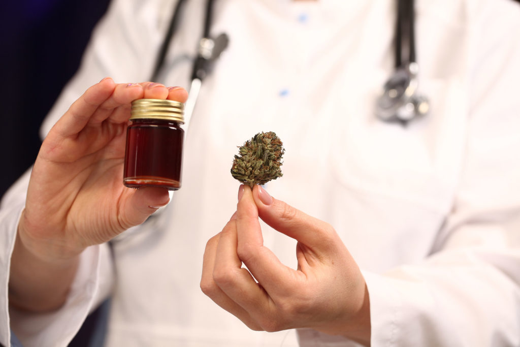 A doctor holding a small glass jar and a cannabis bud 