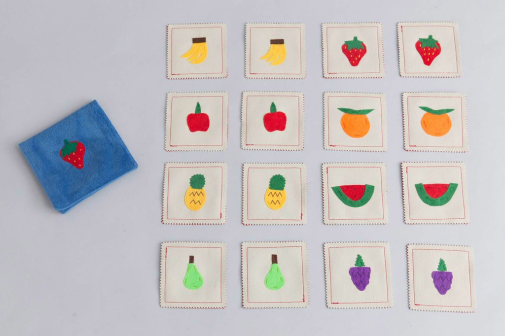 Memory game with fruits painted on the cards on grey surface