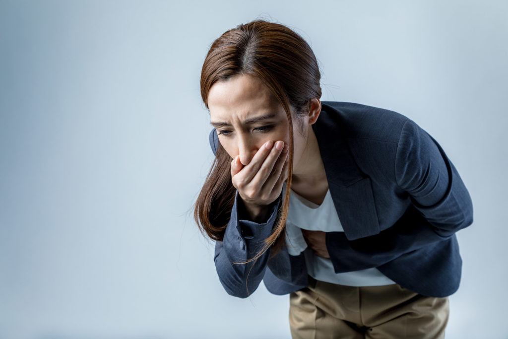 A woman having a nausea, holding hand over the mouth