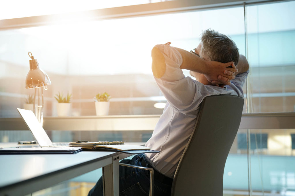 Un homme reposant avec les bras soutenant sa tête au bureau