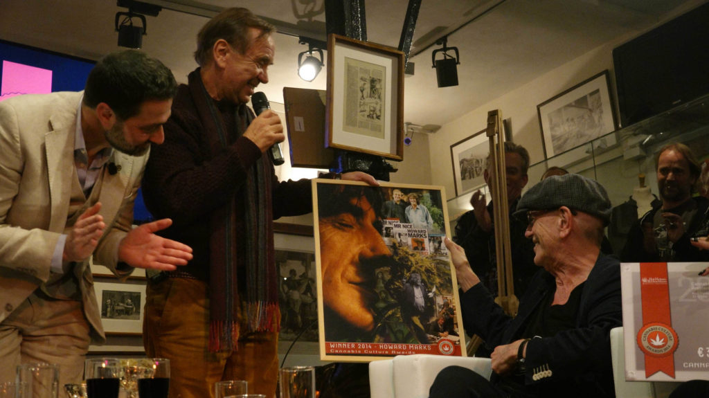 Drie mannen kijken naar een poster op het podium in de Cannabis Culture Awards