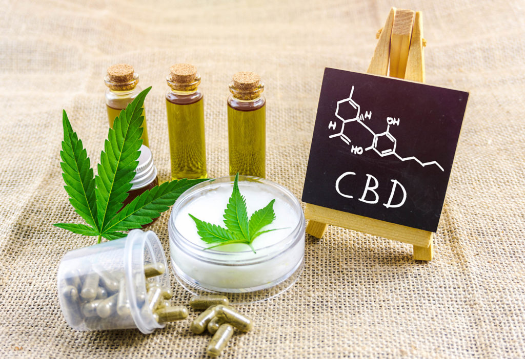 La formule chimique de CBD sur un mini-tableau, huile de CBD, capsules et crème