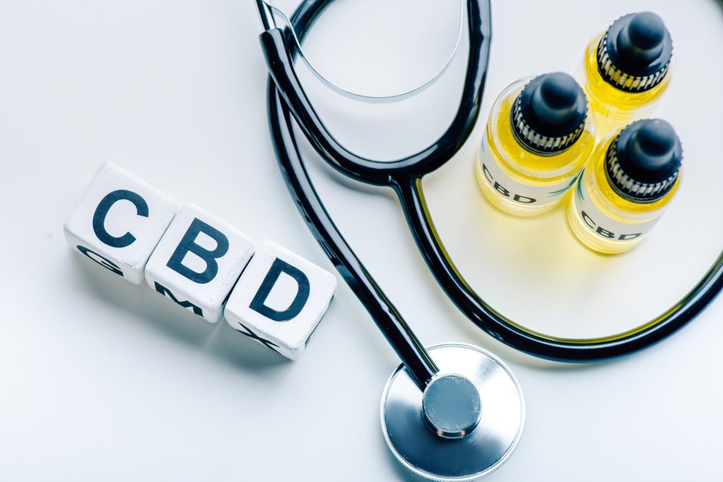 Blocks spelling out CBD, a stethoscope and three bottles of CBD oil