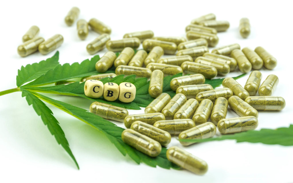 A cannabis leaf and a handful of brown pill capsules