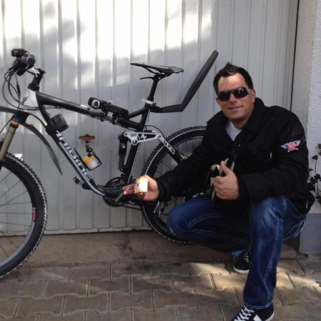 Chris Vrzak bending down next to a bicycle