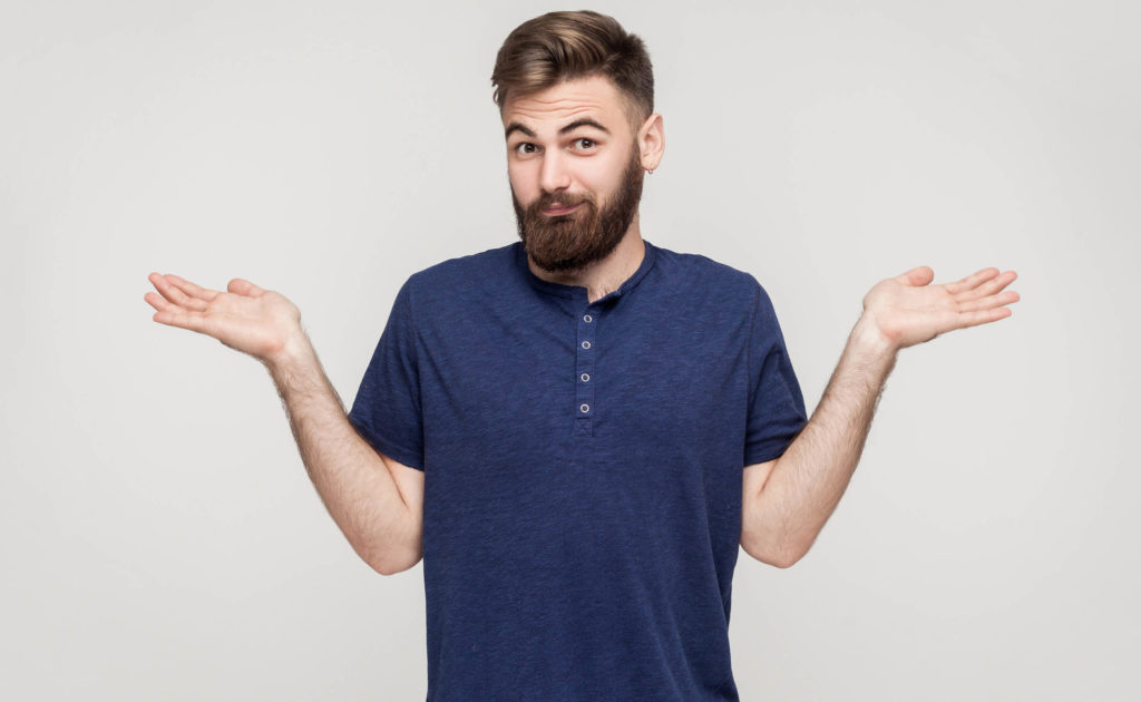 Ein Mann in einem blauen T-Shirt, das seine Hände heraus hält und seine Schultern zuckt