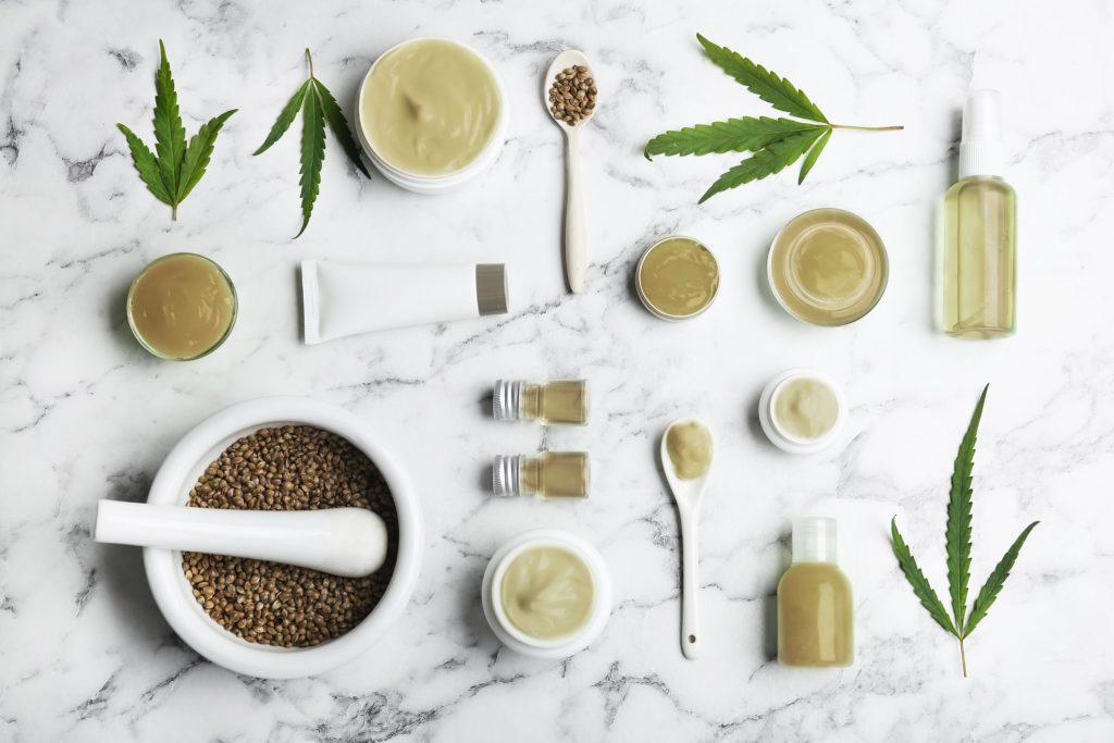 Hemp skincare products laid out on a table next to cannabis leaves