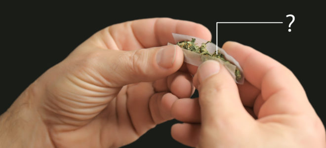 Une personne qui roule un joint contre le fond noir