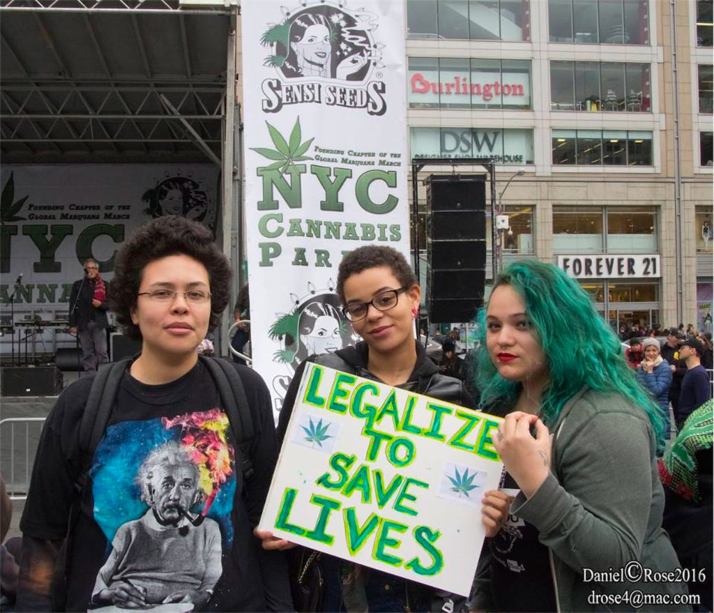 Tres mujeres en el desfile de cannabis de Nueva York con un cartel "Legalice para salvar vidas"