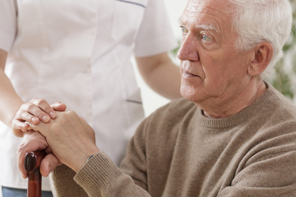 Un trabajador médico sosteniendo una mano de un anciano