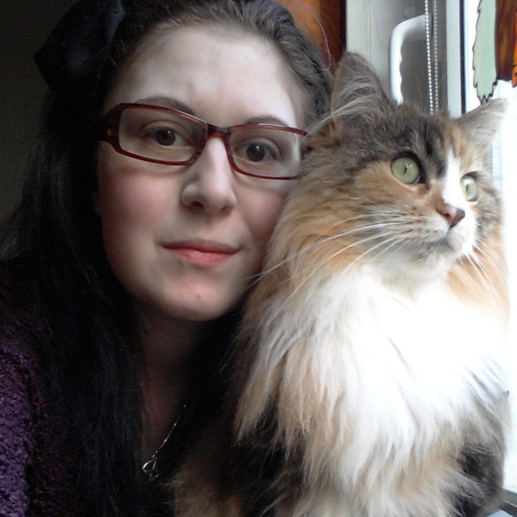 Peggy S. wearing glasses with a cat beside her