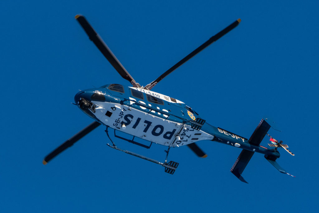 Een politiehelikopter die tegen de blauwe hemel op de achtergrond vliegt