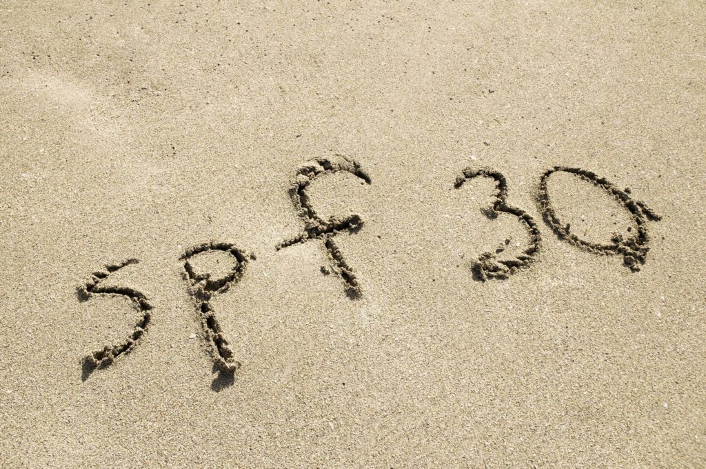 Strand und geschriebene „SPF 30“ im Sand