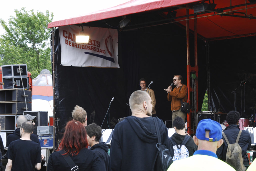 Two men performing on an outdoor stage to a large crowd