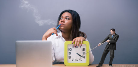 A woman sat at a desk looking into the distance with her hand on a clock