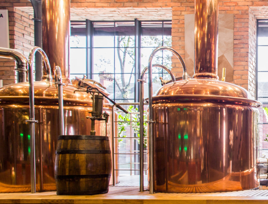 El interior de una cervecería con dos grandes hervidores de cobre.