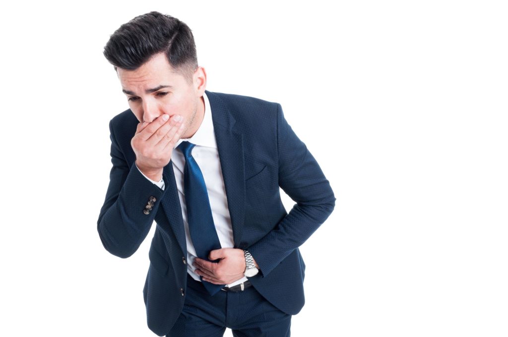 Un hombre en un traje con luchando por no vomitar contra el fondo blanco.