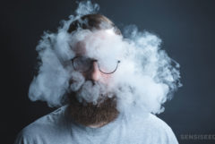 Un hombre con barba y vasos rodeados de humo de cannabis.