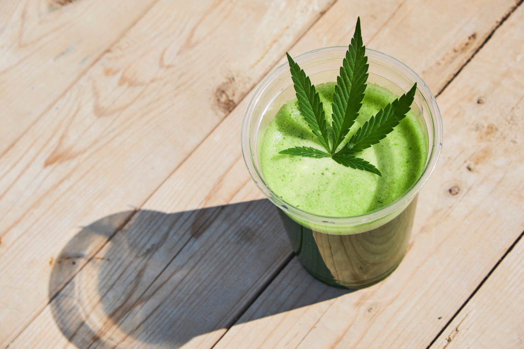 Cannabis juice in transparent plastic glass, with a cannabis leaf on top