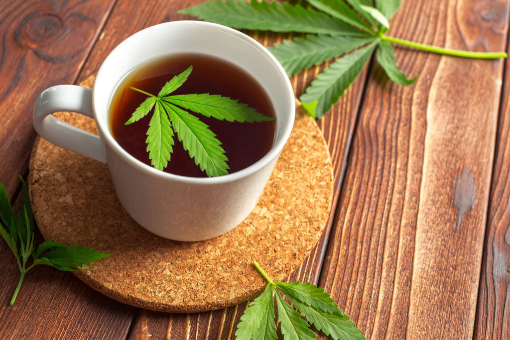 A white mug of cannabis tea on a cork coaster