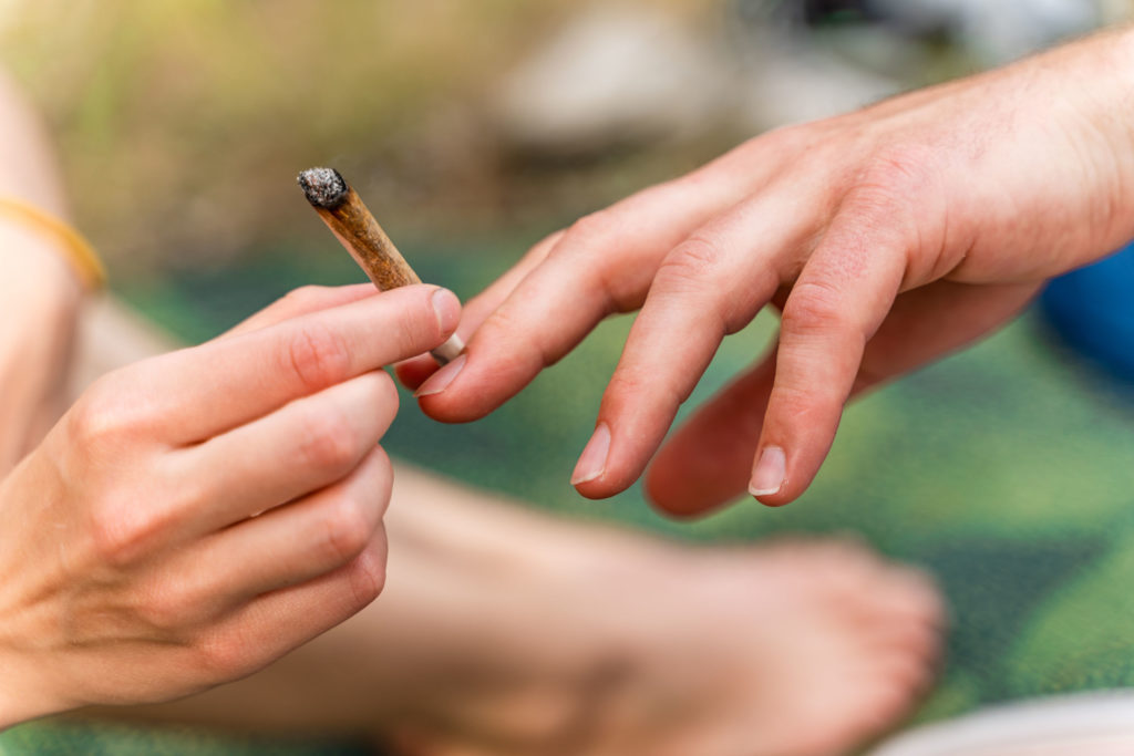 Une personne qui passe une autre personne un joint éclairé