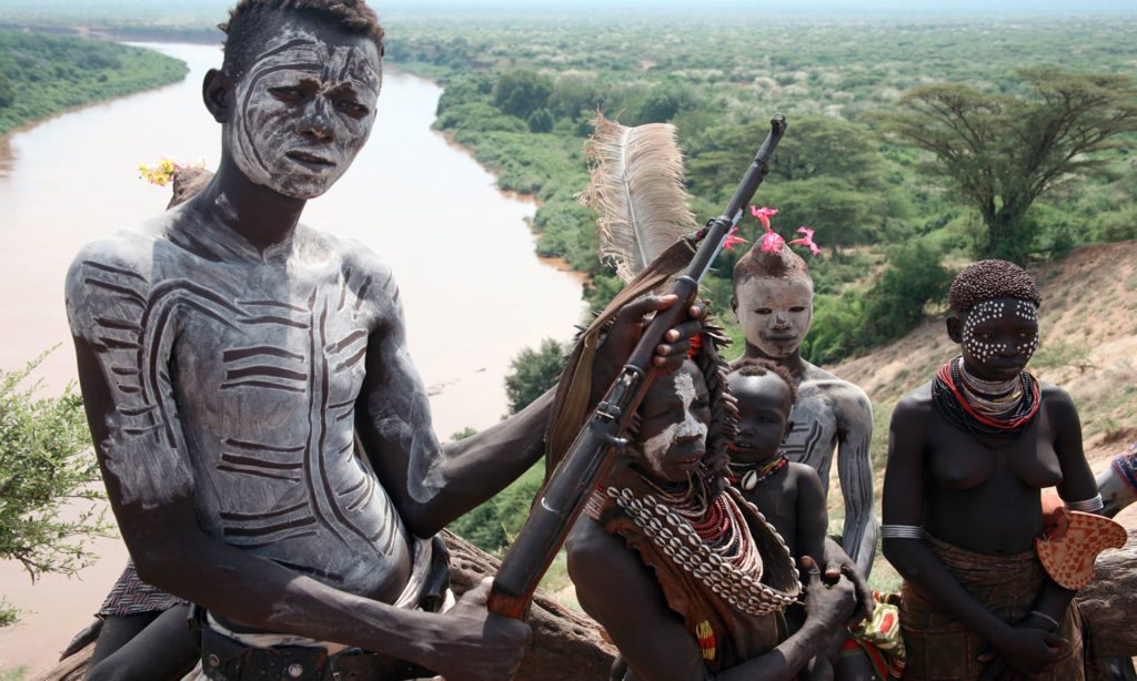 Five child soldiers covered in paint and carrying guns