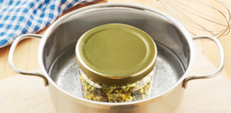 Ein Kochtopf mit kochendem Wasser und einem Glas mit Cannabis