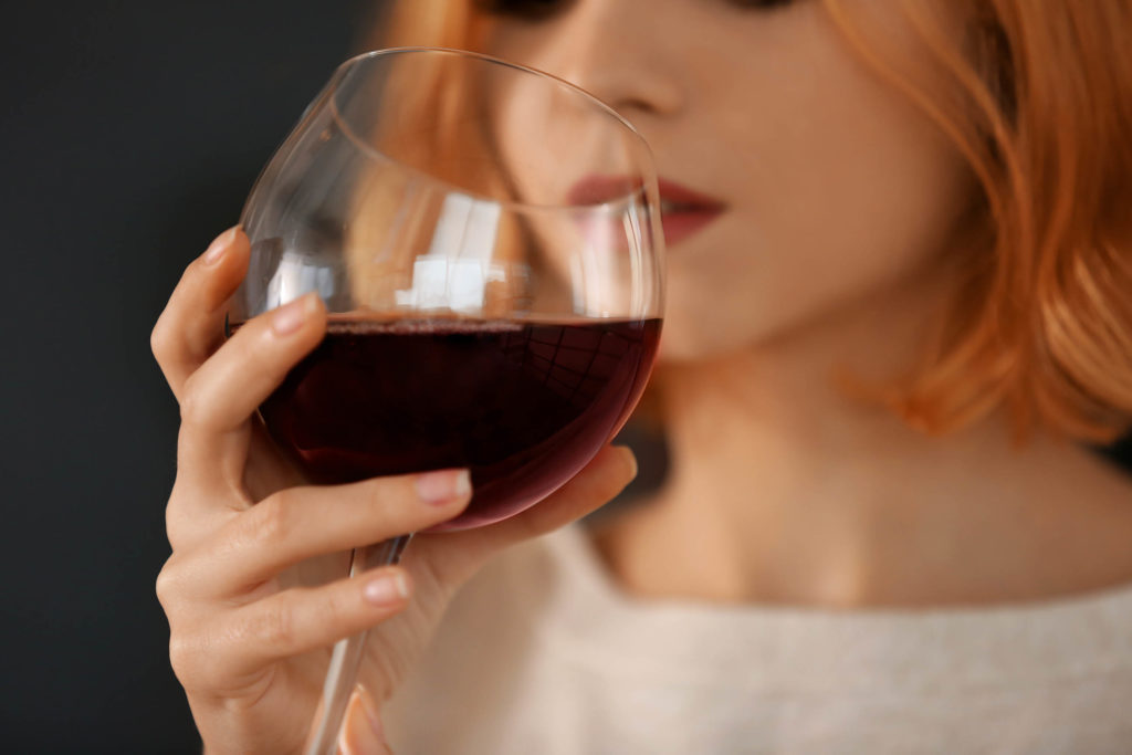 A woman drinking red wine from a wine glass