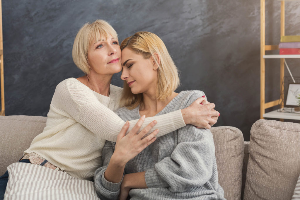 An older woman comforting another younger woman with her arms around her